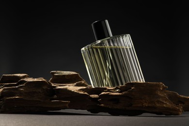 Photo of Luxury men`s perfume in bottle on grey table against dark background, space for text