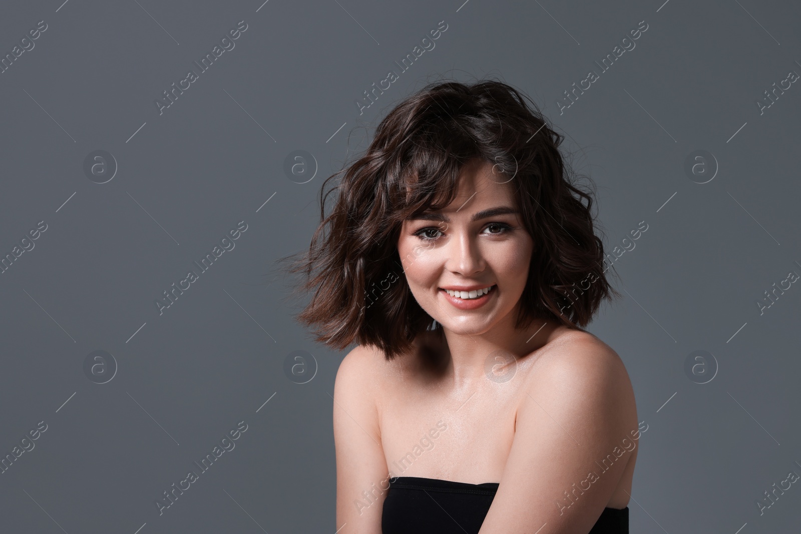 Photo of Portrait of beautiful young woman with wavy hairstyle on grey background. Space for text