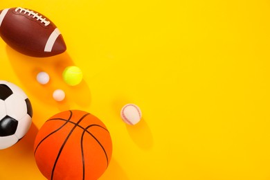 Photo of Many different sports balls on yellow background, flat lay. Space for text