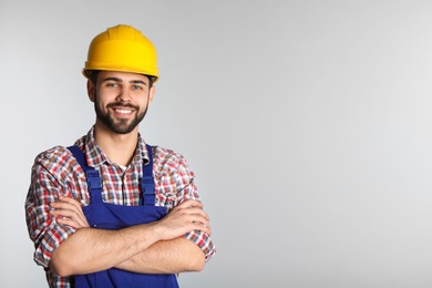 Portrait of construction worker in uniform on light background, space for text