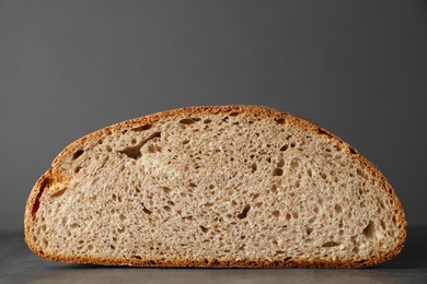 Photo of Piece of freshly baked sourdough bread on grey table, closeup