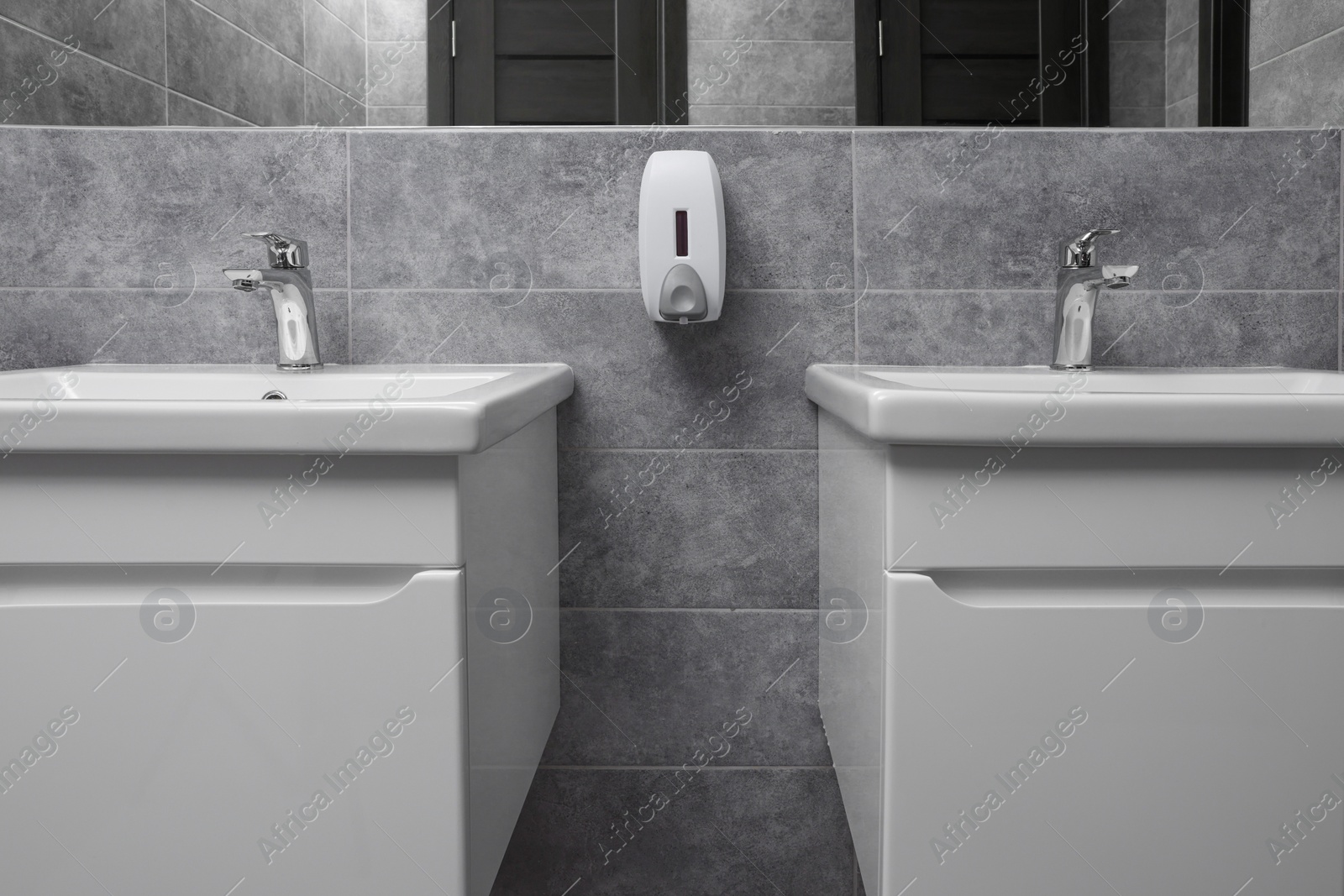 Photo of Public toilet interior with stylish white sinks and grey tiles