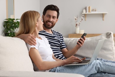 Photo of Happy couple with laptop on sofa at home