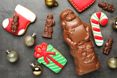 Photo of Flat lay composition with chocolate Santa Claus candies and Christmas cookies on grey table