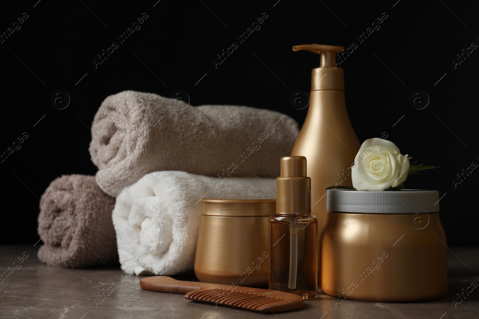 Photo of Different hair products, rolled towels and comb on grey table