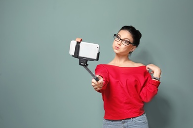 Photo of Attractive young woman taking selfie on grey background