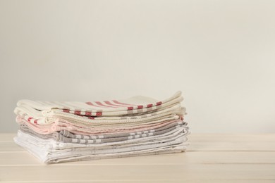 Photo of Stacked kitchen towels on white wooden table, space for text