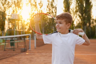 Photo of Cute little boy with tennis racket on court outdoors