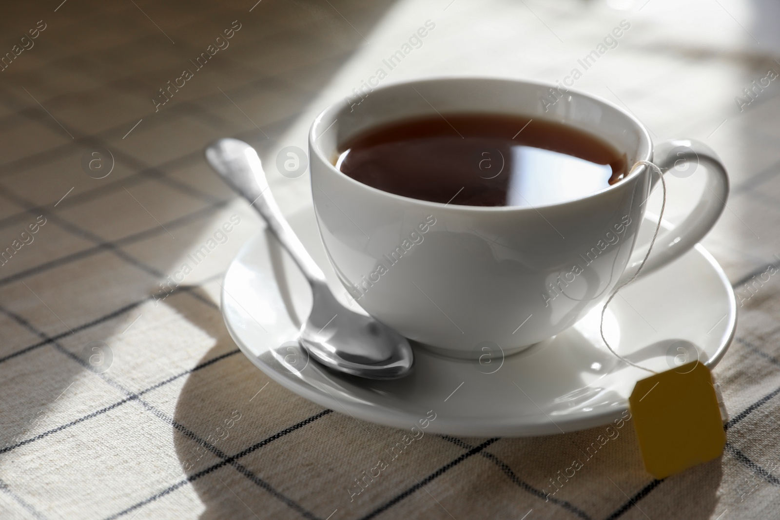 Photo of Bag of black tea in cup on table, closeup. Space for text