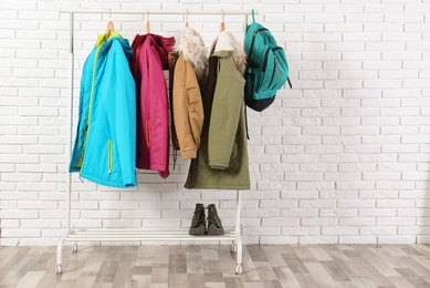 Shoes and clothes on hanger stand against brick wall. Idea for interior decor