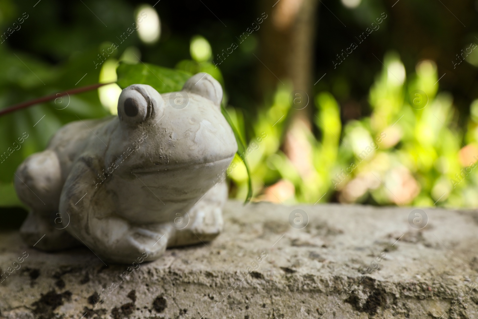 Photo of Frog figure on stone parapet outdoors. Space for text