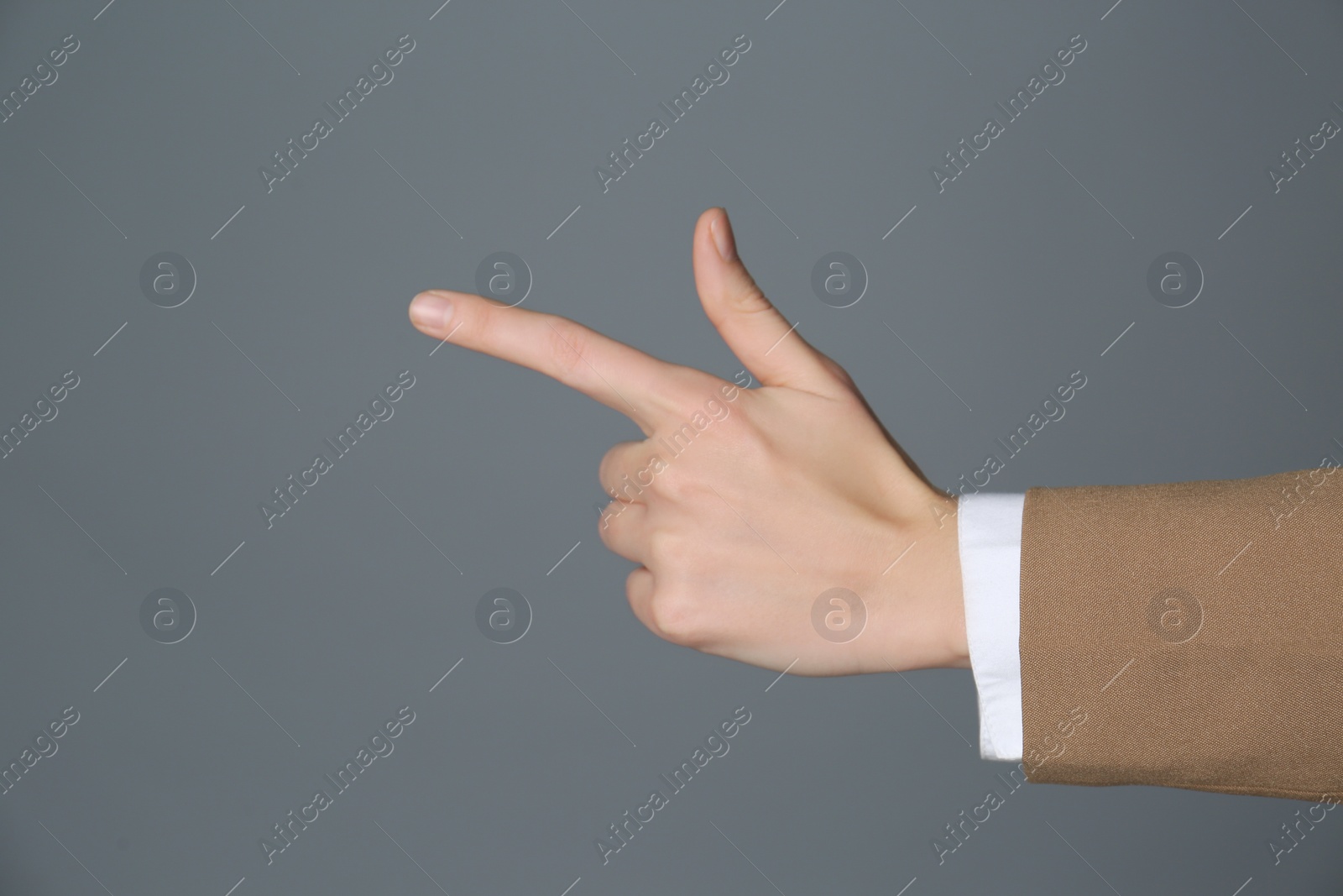 Photo of Businesswoman pointing at something on grey background, closeup. Finger gesture