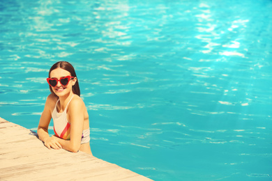 Image of Beautiful young woman in swimming pool on sunny day