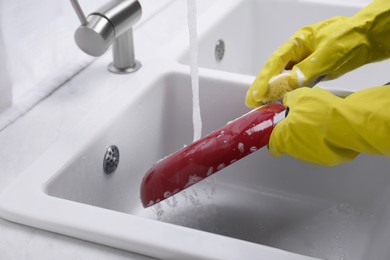 Woman washing frying pan with sponge in kitchen sink, closeup