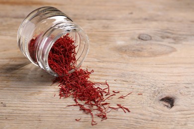 Photo of Aromatic saffron in glass jar on wooden table, space for text