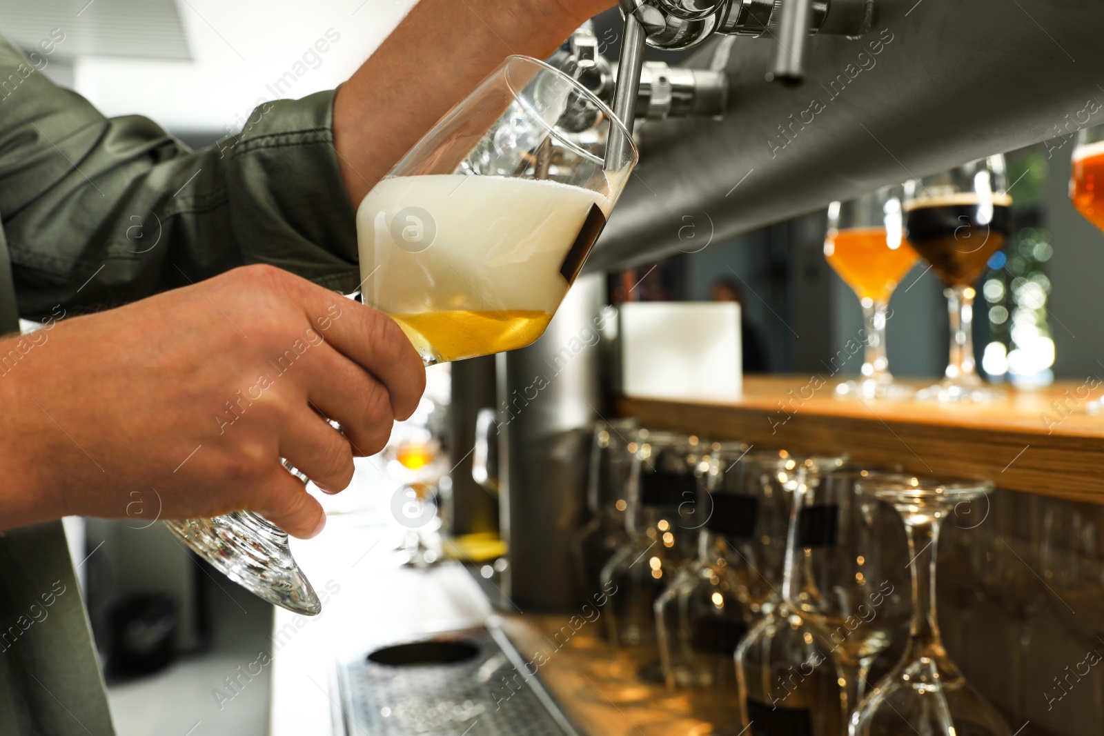 Photo of Bartender pouring fresh beer into glass in pub, closeup