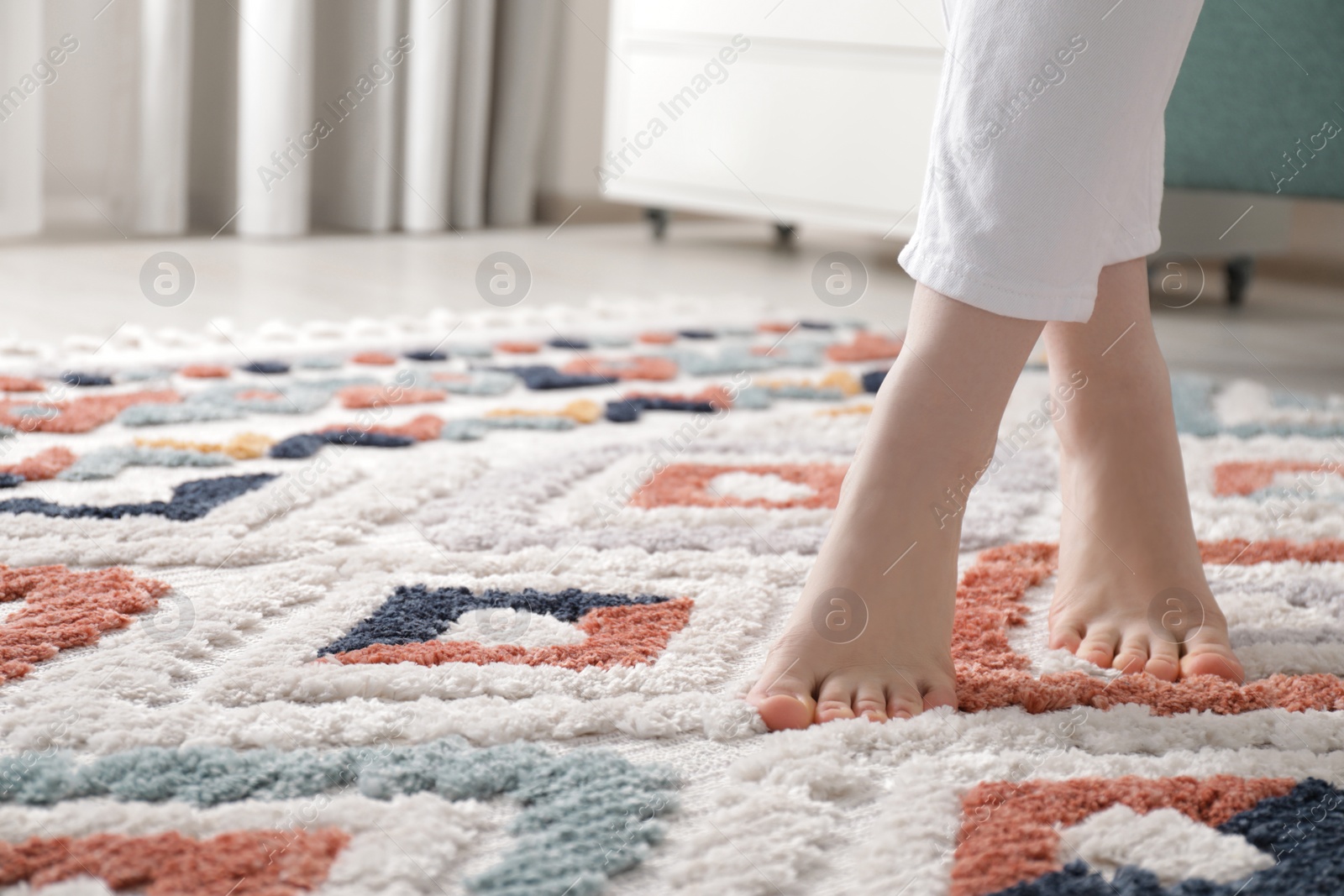 Photo of Woman standing on carpet with pattern at home, closeup. Space for text