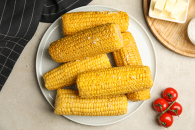 Photo of Delicious boiled corn served on light grey table, flat lay