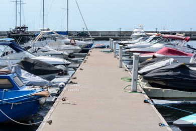 Photo of Beautiful view of city pier with moored boats and water scooters on sunny day