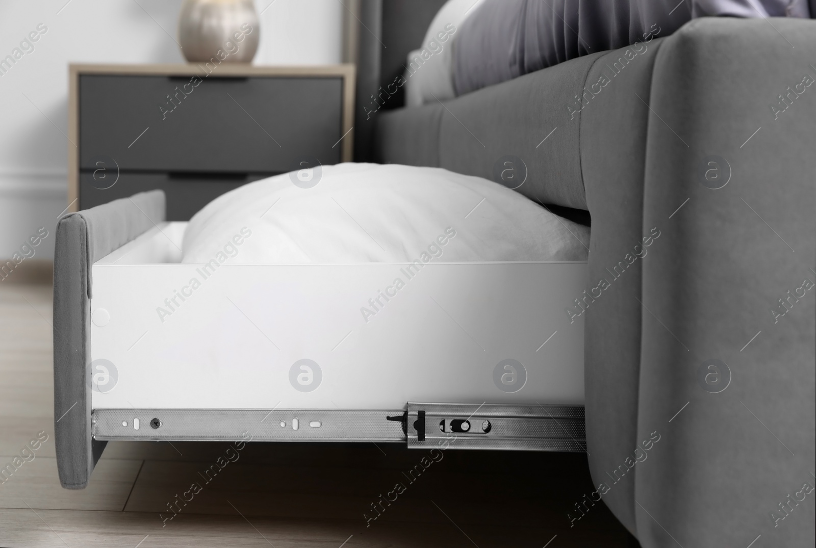 Photo of Storage drawer with white pillow under modern bed in room