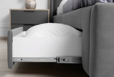 Storage drawer with white pillow under modern bed in room