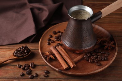 Cezve with Turkish coffee, beans and spices on wooden table, space for text