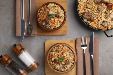 Photo of Delicious pilaf and spices served on grey textured table, flat lay