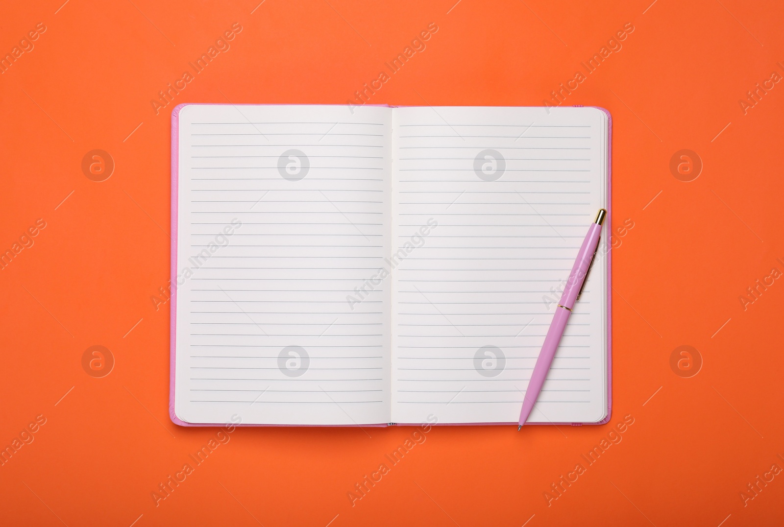 Photo of Open blank notebook and pen on orange background, top view