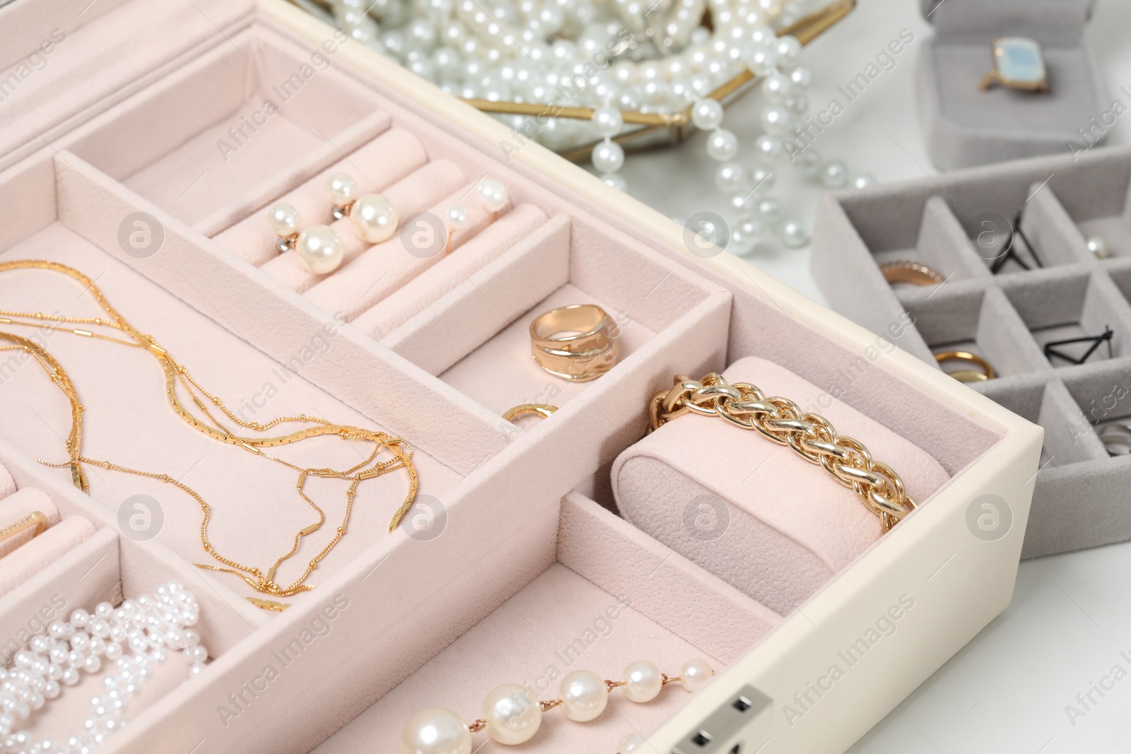 Photo of Jewelry boxes with many different accessories on white table, closeup