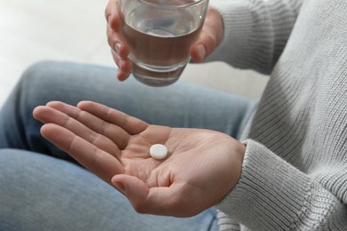 Photo of Man with glass of water and pill on blurred background, closeup