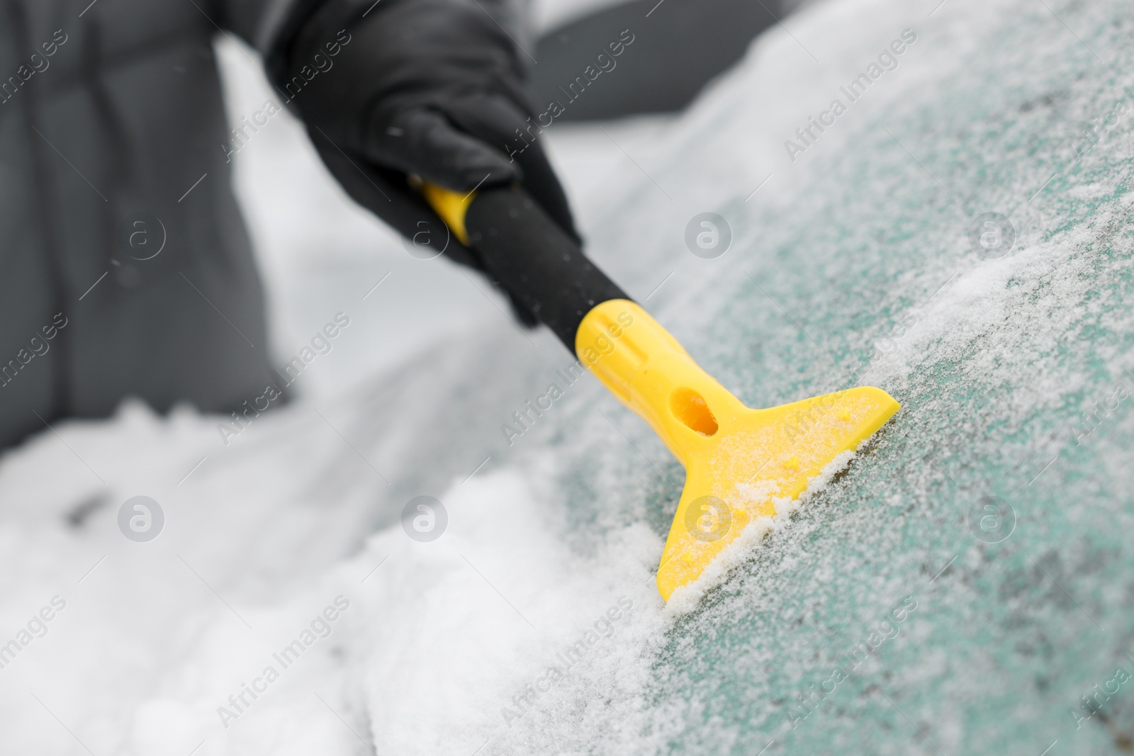 Photo of Man cleaning snow from car windshield outdoors, closeup