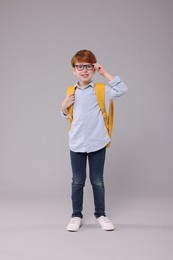 Photo of Happy schoolboy with backpack on grey background