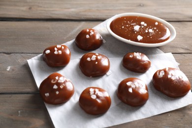 Tasty candies, caramel sauce and salt on wooden table