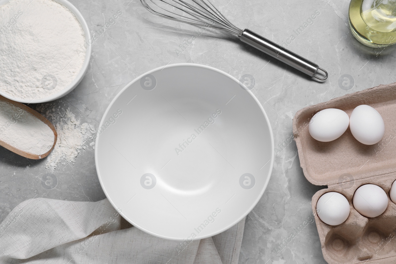 Photo of Making tasty baklava. Bowl, whisk, flour and eggs on light grey marble table, flat lay