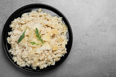Photo of Delicious risotto with cheese on grey table, top view. Space for text