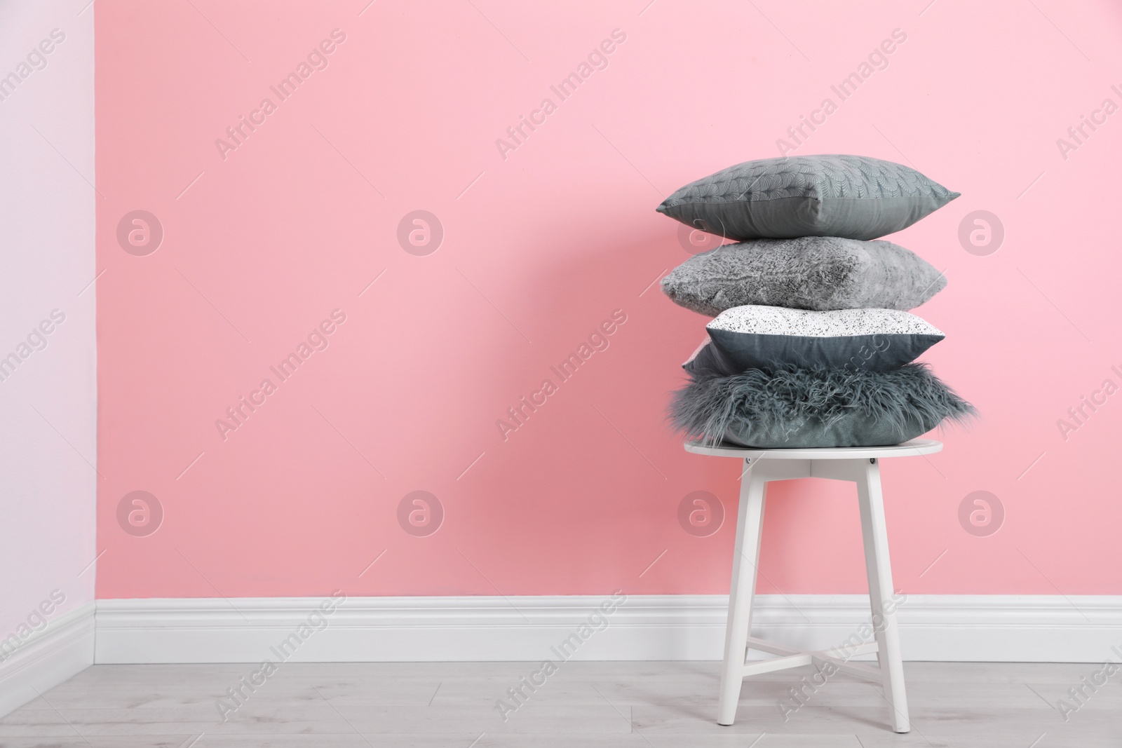 Photo of Many different pillows on chair near color wall with space for text