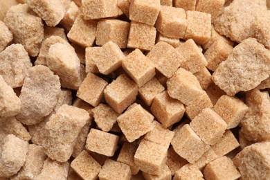 Different pieces of refined brown sugar as background, closeup