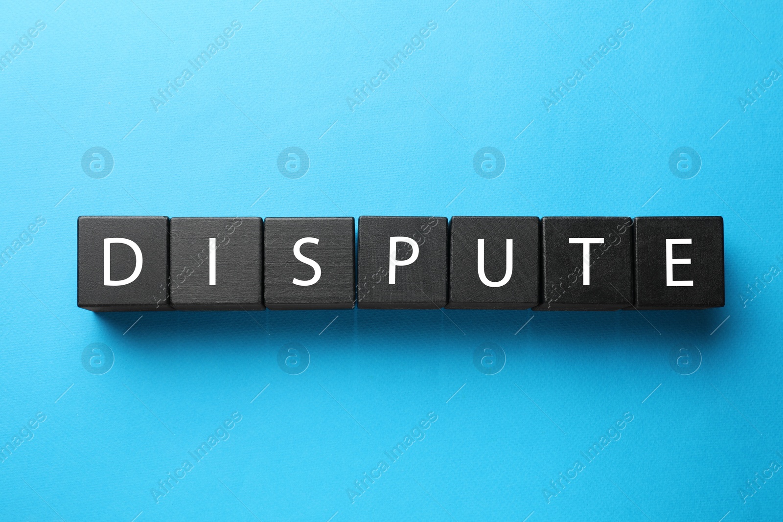 Photo of Word Dispute made with black cubes on light blue background, top view