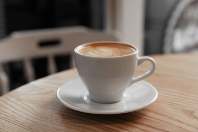 Photo of Cup of aromatic hot coffee on wooden table in cafe