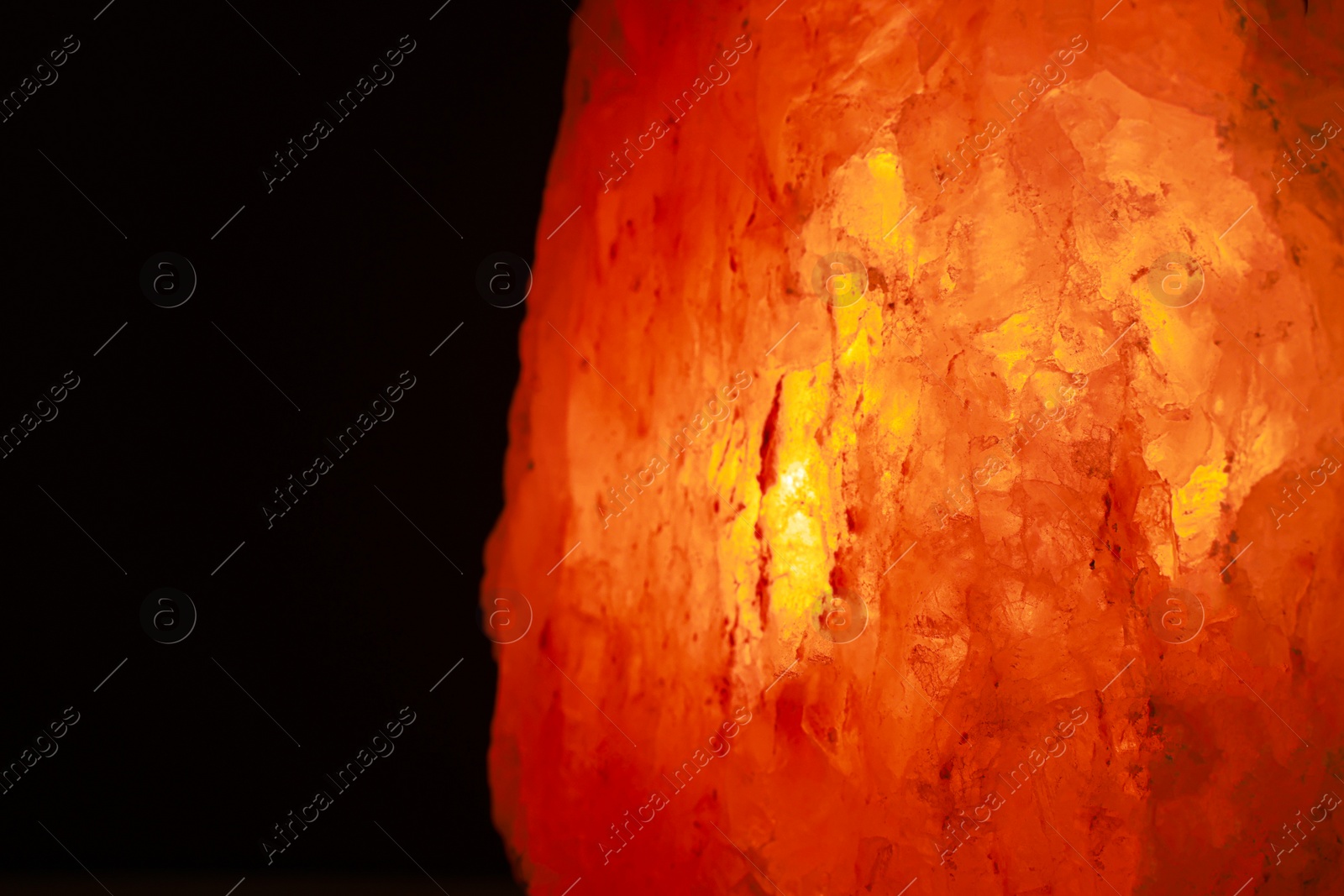 Photo of Himalayan salt lamp on dark background, closeup