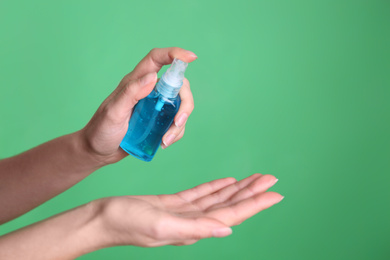 Photo of Woman applying antiseptic gel on green background, closeup