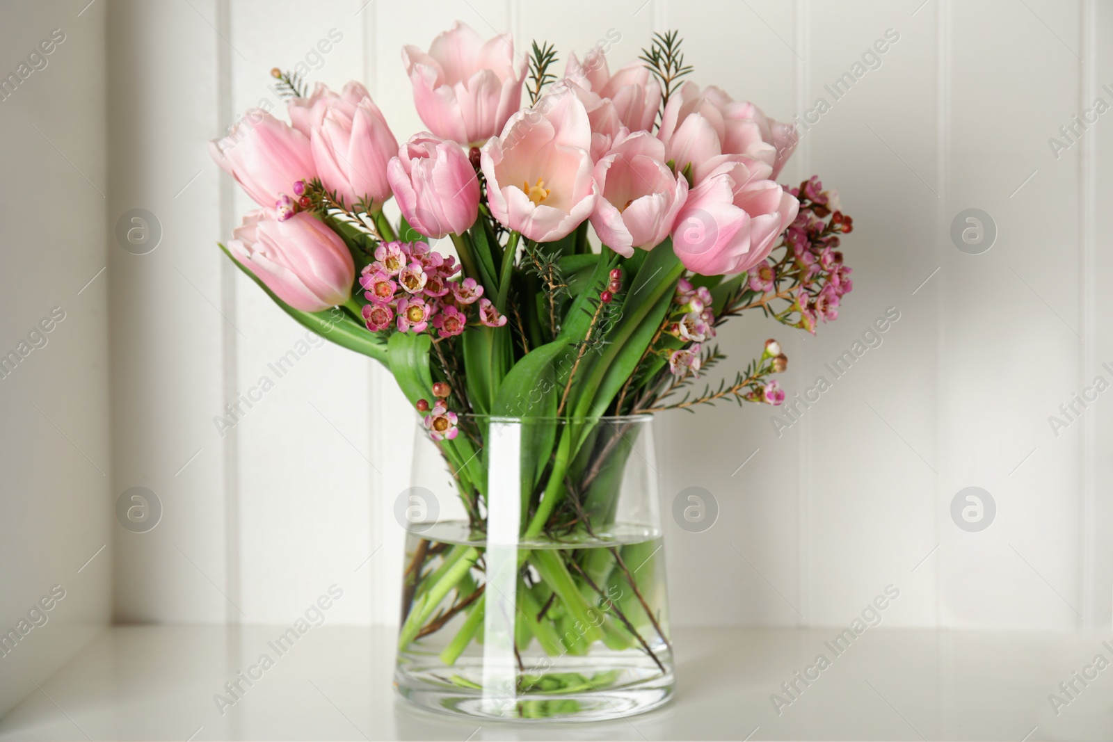 Photo of Beautiful bouquet with spring pink tulips on shelf