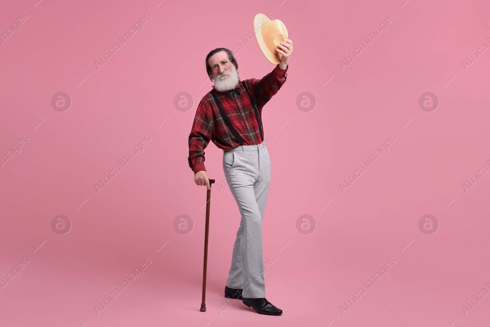 Photo of Senior man with hat and walking cane on pink background