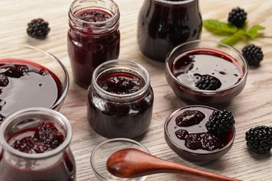 Photo of Tasty blackberry jam and fresh berries on white wooden table