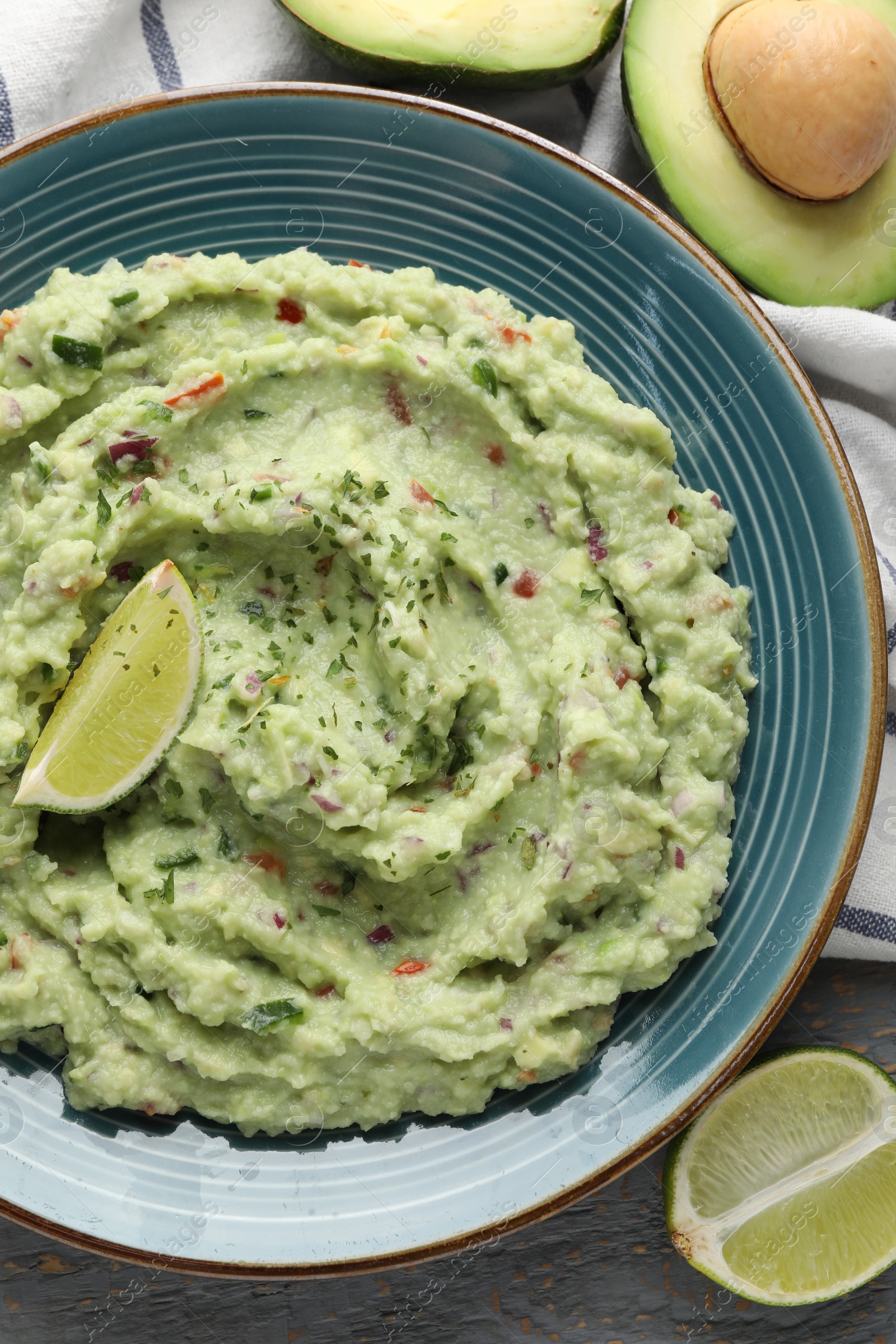 Photo of Delicious guacamole with lime and fresh avocado on table, flat lay