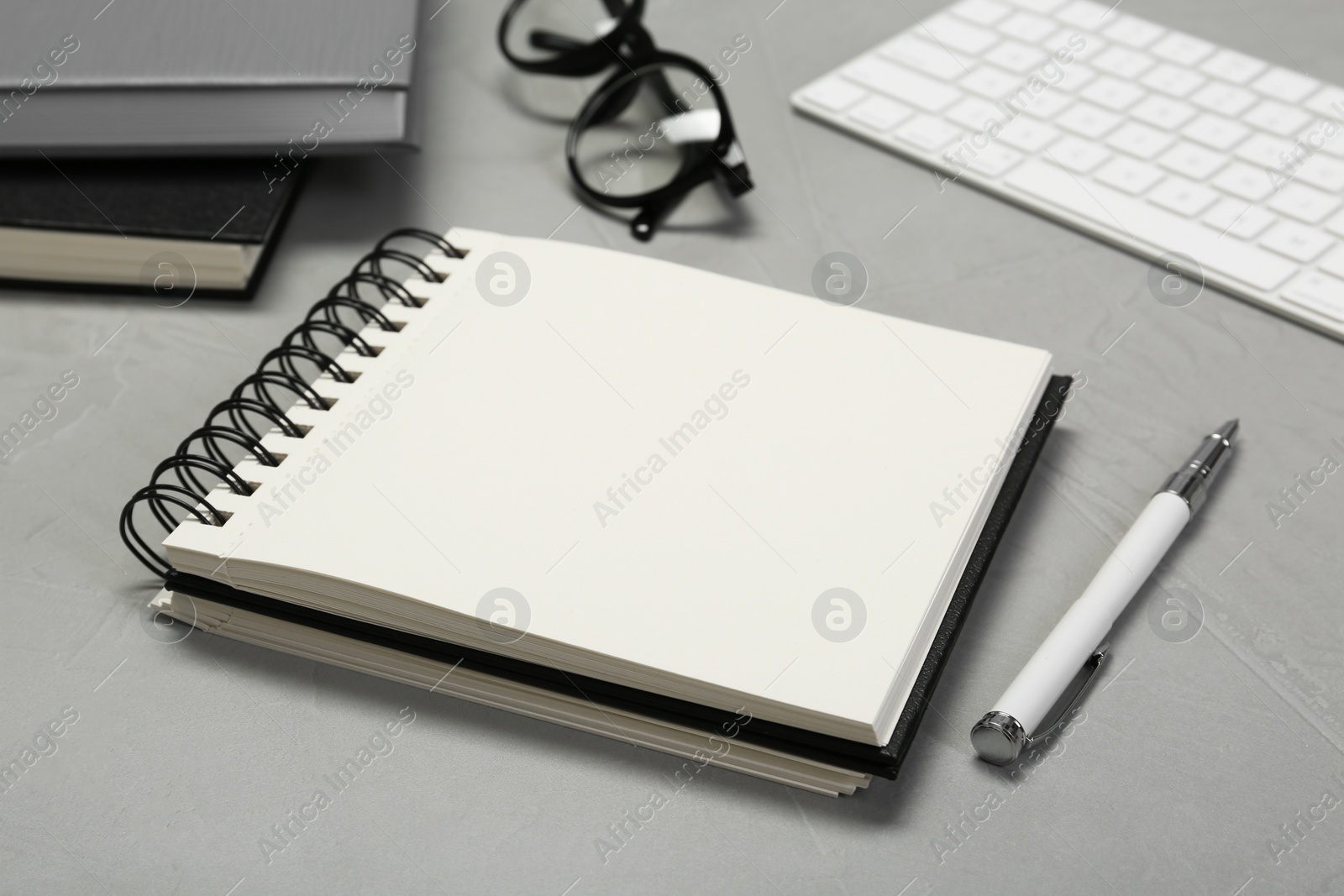 Photo of Open notebook and pen on light grey table