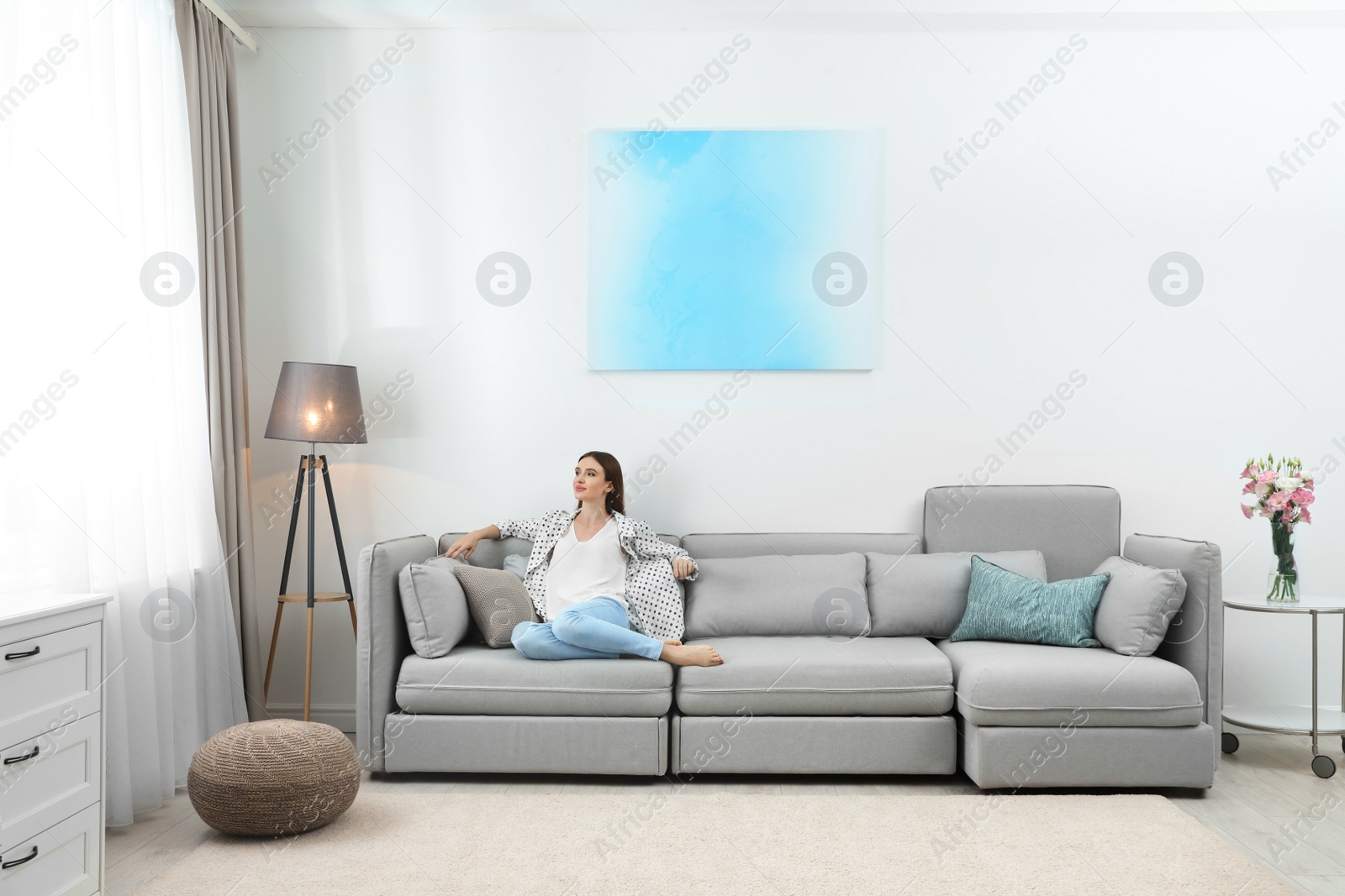 Photo of Happy young woman sitting under air conditioner at home