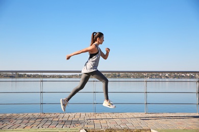 Sporty woman running outdoors on sunny morning