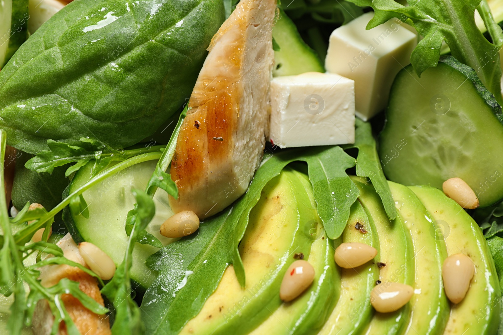 Photo of Delicious salad with chicken, arugula and avocado as background, closeup