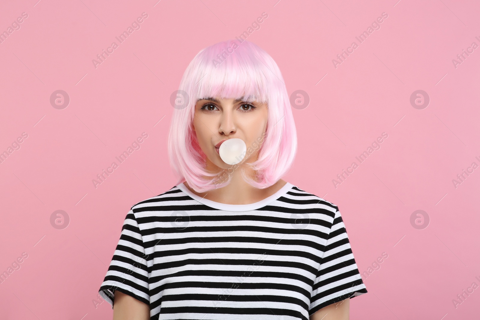 Photo of Beautiful woman blowing bubble gum on pink background